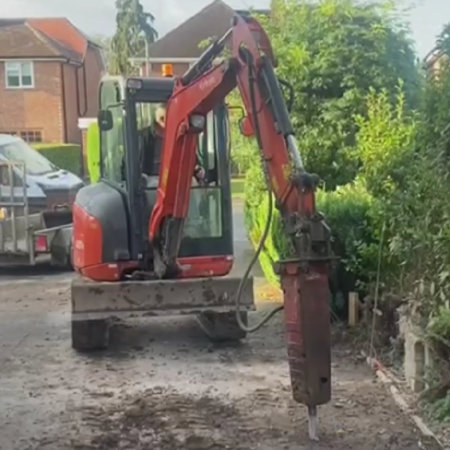 Breaking concrete with hammer Bit on small digger